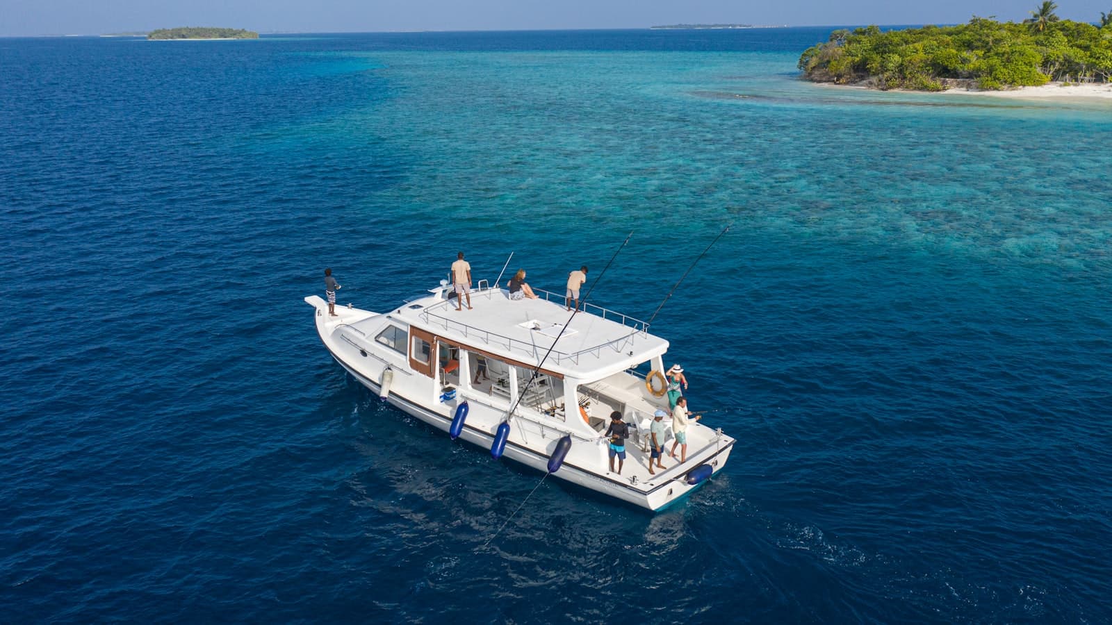 青い海に浮かぶ白いダイビングボートと乗船するダイバーたち